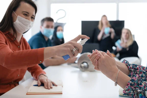 Novos empresários normais em reunião usando antibacteriano higienizador da mão — Fotografia de Stock