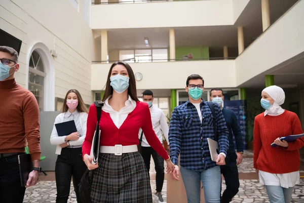 Studentgrupp på universitetet promenader och bär ansiktsmask — Stockfoto