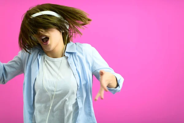 Brunette lady in black glasses dancing and listening music isolate on pink background — Stock Photo, Image