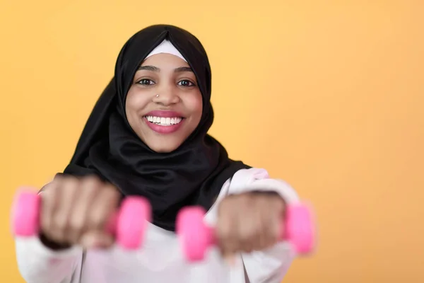 Afro-muslimische Frau fördert ein gesundes Leben, indem sie Hanteln in ihren Händen hält — Stockfoto
