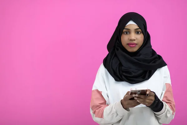 Afro-Frau benutzt Handy vor rosa Hintergrund — Stockfoto