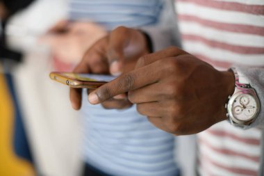 diverse teenagers use mobile devices while posing for a studio photo in front of a pink background clipart