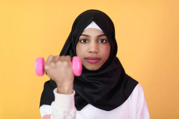 Afro musulmana mujer promueve una vida saludable, sosteniendo mancuernas en sus manos — Foto de Stock