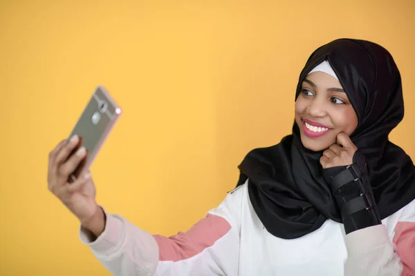 Afrikanska muslimska kvinna med ett vackert leende tar en selfie med en mobiltelefon — Stockfoto