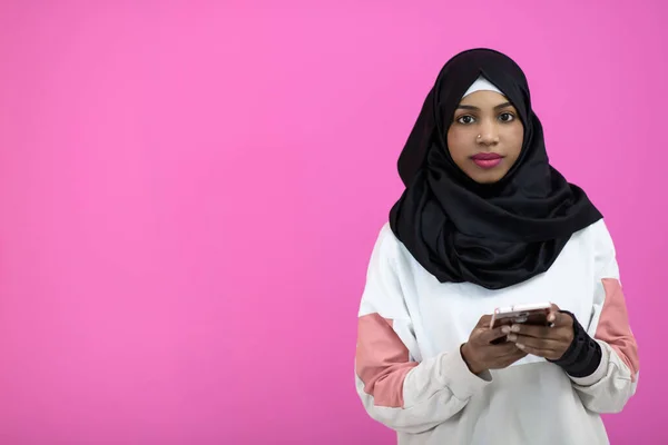 Afro žena používá mobilní telefon před růžovým pozadím — Stock fotografie