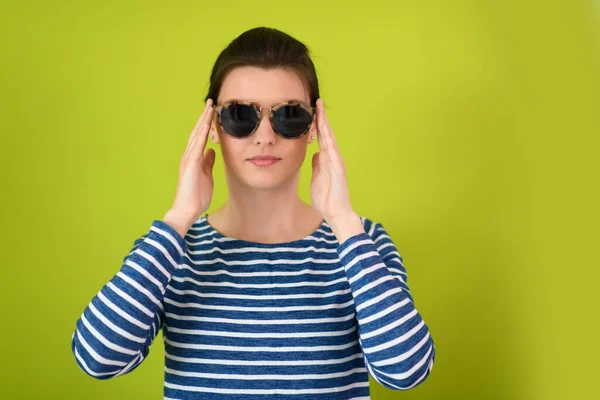 Femme en lunettes de soleil posant devant un fond vert — Photo