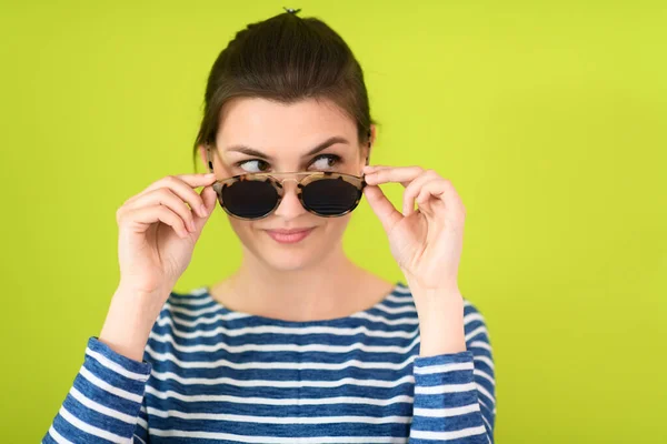 Donna in occhiali da sole posa davanti a uno sfondo verde — Foto Stock