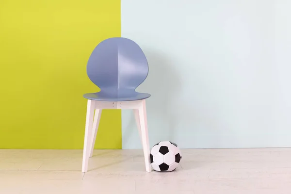 Moderna cadeira azul e bola de futebol na frente de um fundo azul verde — Fotografia de Stock