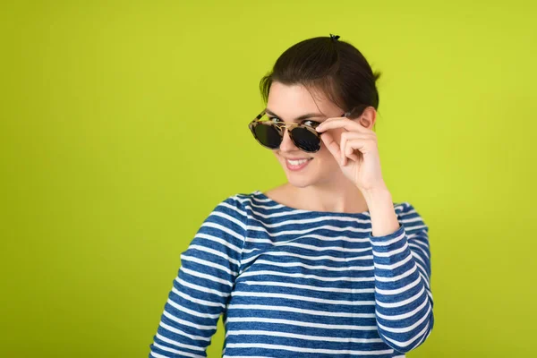 Γυναίκα με γυαλιά ηλίου ποζάρουν μπροστά από ένα πράσινο φόντο — Φωτογραφία Αρχείου