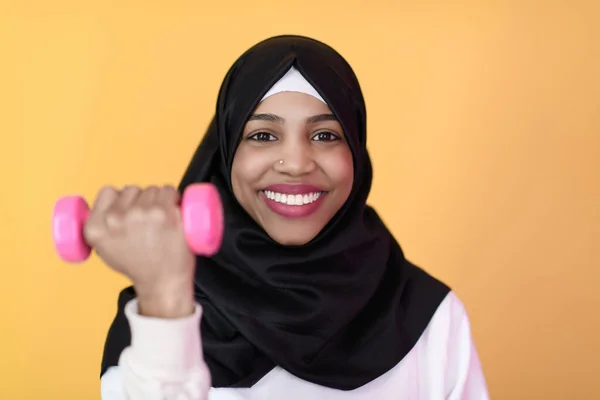 Afro musulmana mujer promueve una vida saludable, sosteniendo mancuernas en sus manos — Foto de Stock