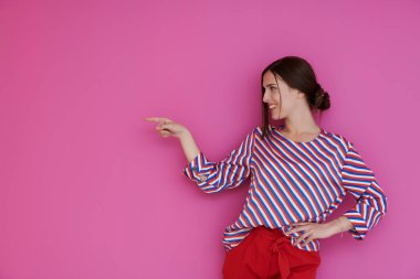 Mutlu, genç bir bayan kameraya geniş bir gülümseme ile işaret ederek, ilginç ve heyecan verici bir şey göstermek stüdyo duvarında metin veya reklam içeriği için kopya alanı ile