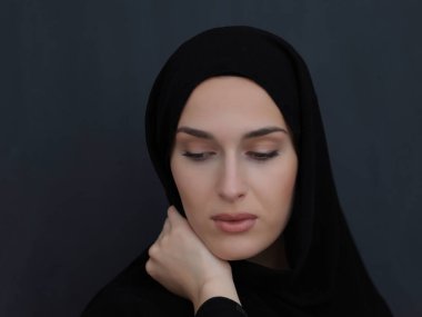 Siyah abaya giymiş modern müslüman bir kadının portresi. Geleneksel kıyafetler giyen ve siyah karatahtanın önünde poz veren Arap bir kız. Modern ve zengin Arap yaşam tarzını temsil ediyor