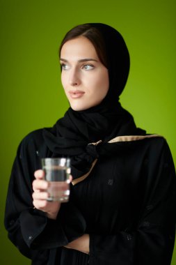 Abaya 'daki modern Müslüman kadın önünde bir bardak su tutuyor. İftar zamanını temsil eden Arap kız, Ramazan kareem kavramı