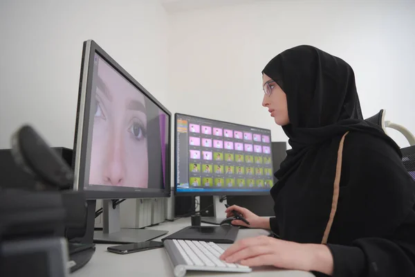 Young muslim girl working on the computer from home. Female photo editor at working place. Freelancer using two monitors while doing job