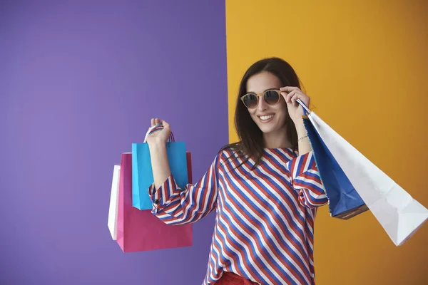 カラフルな背景にショッピングバッグを持つ若い女性 大販売の1日後に新しい購入でポーズをとっている幸せな女の子 ブラック フライデーのコンセプト — ストック写真