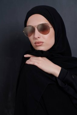 Geleneksel giysiler içinde genç Müslüman iş kadını ya da abaya ve siyah karatahtanın önünde poz veren güneş gözlüğü. Modern Arap yaşam tarzını, İslami modayı ve Ramazan kareemini temsil eden Arap kadını