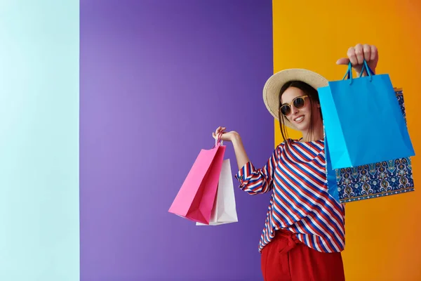 Jeune femme avec des sacs à provisions sur fond coloré — Photo