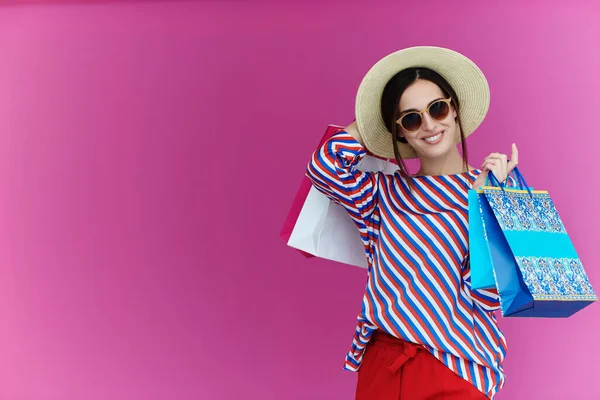 Mujer joven con bolsas de compras sobre fondo rosa —  Fotos de Stock