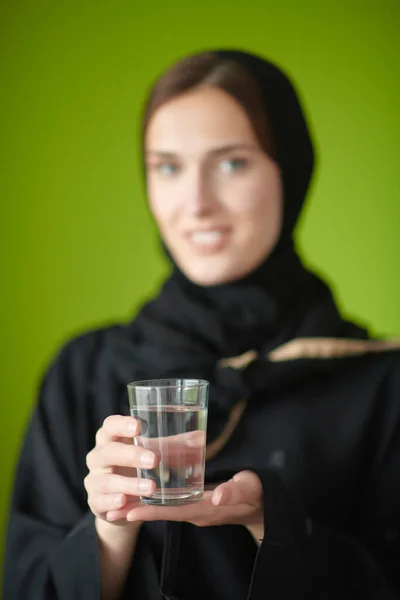 Közel-keleti nő abayában, kezében egy pohár vízzel. — Stock Fotó