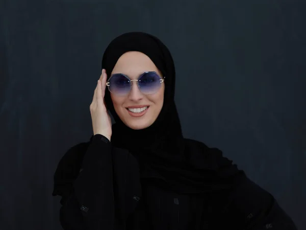 伝統的な服や黒の黒板の前にポーズをとるアバヤやサングラスの若いイスラム教徒 現代のアラブのライフスタイル イスラムファッション ラマダーンカレムの概念を表すアラブ女性 — ストック写真