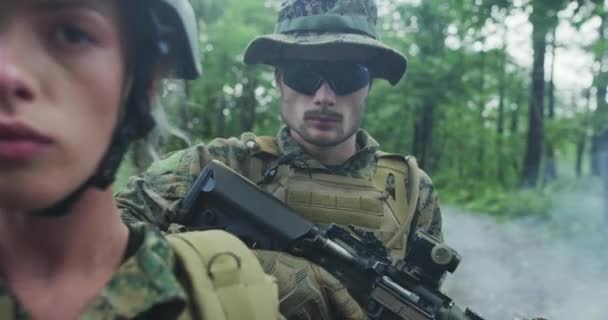 Squadra di soldati di pattuglia attraverso l'area forestale, squadra con solidali maschi e femmine in una fitta foresta con fumo in backgorund — Video Stock