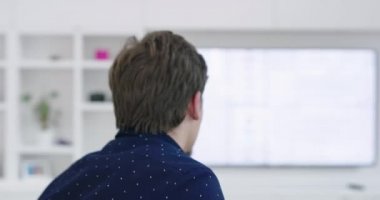 Kanepede oturan ve modern evde gülümseyen bir adam.