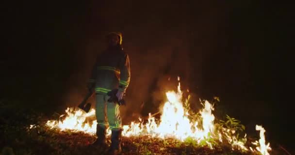 Портрет пожарного с полным снаряжением, держит топор в руке — стоковое видео