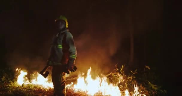 Портрет пожарного с полным снаряжением, держит топор в руке — стоковое видео
