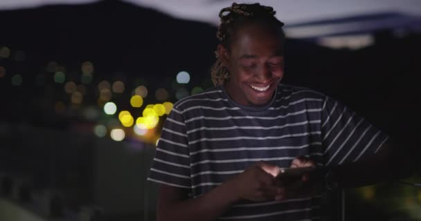 Afro americano uomo utilizzando smartphone in notte città luci backgorund — Video Stock