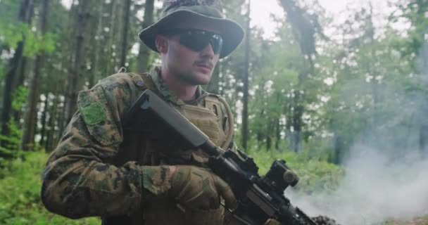 Moderner Soldat mit Gewehr im Wald mit Rauch im Hintergrund — Stockvideo