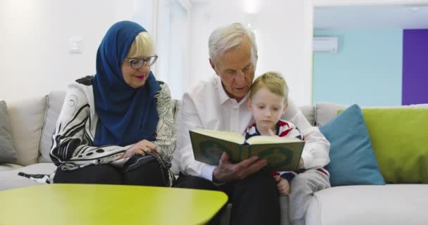 Muslimische Familie Generationen Großeltern lesen Koran mit Enkeln zu Hause — Stockvideo