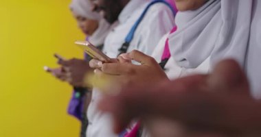Afrikalı öğrenci grubu renkli arka planda akıllı telefonlar kullanıyor