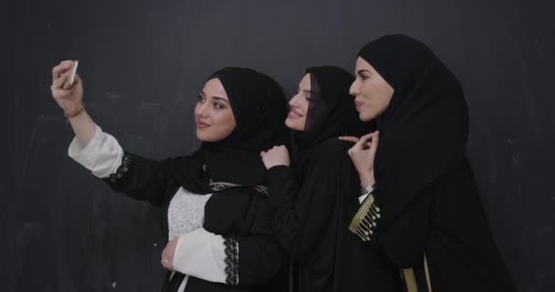 Grupp unga vackra muslimska kvinnor i moderiktig klänning med hijab med mobiltelefon tar selfie — Stockvideo