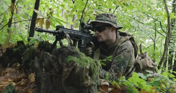 Soldado de espingarda totalmente equipado usando uniforme de camuflagem atacando inimigo, rifle em posição de disparo na floresta densa — Vídeo de Stock