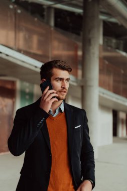 Modern bir ofis binasının şantiyesini denetlerken akıllı telefon kullanan işadamı mimar.