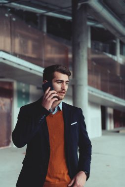 Modern bir ofis binasının şantiyesini denetlerken akıllı telefon kullanan işadamı mimar.