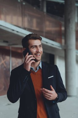 Modern bir ofis binasının şantiyesini denetlerken akıllı telefon kullanan işadamı mimar.