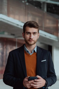 Modern bir ofis binasının şantiyesini denetlerken akıllı telefon kullanan işadamı mimar.