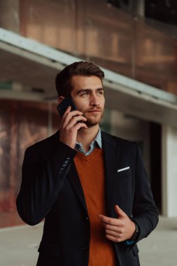 Modern bir ofis binasının şantiyesini denetlerken akıllı telefon kullanan işadamı mimar.