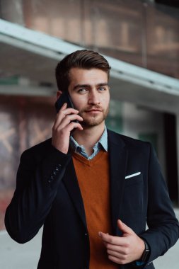 Modern bir ofis binasının şantiyesini denetlerken akıllı telefon kullanan işadamı mimar.