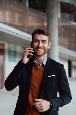 Modern bir ofis binasının şantiyesini denetlerken akıllı telefon kullanan işadamı mimar.