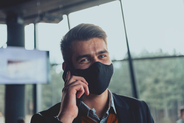 Corporate businessman wearing a protective medical face mask at modern open space office concept of new normal in business
