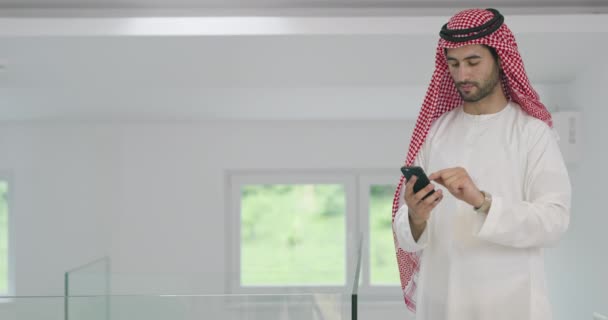 Arabian affärsman bär traditionella kläder när du använder smartphone hemma — Stockvideo