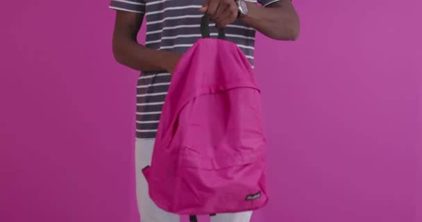 Ung vacker svart man som bär en ryggsäck och ler över rosa bakgrund — Stockvideo