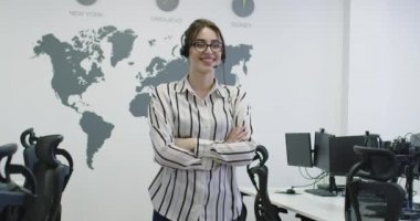 Güzel genç operatör kadın ayakta ve parlak ofis alanında kulaklık takıyor.