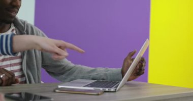 İş yerinin yakınında laptopla iş birliği yapan gülümseyen bir adam ve kadın.