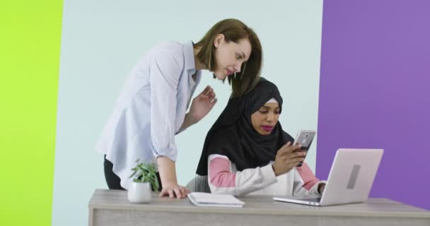 Diversidad Reunión de mujeres étnicas en el cargo. Chica sonriente en Hijab trabajando en el ordenador portátil, rubia mirando la pantalla. — Vídeos de Stock