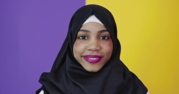 Mulher muçulmana positiva vestindo hijab muçulmano sobre fundo colorido — Vídeo de Stock