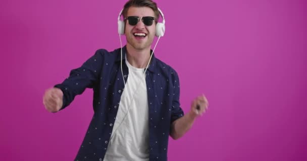 Man dansen en glimlachen over kleur achtergrond tijdens het luisteren naar muziek — Stockvideo