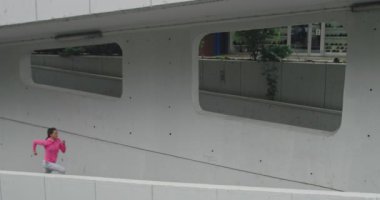 Şehir merkezinde şehir sokağında koşan genç bir bayan sporcu. 